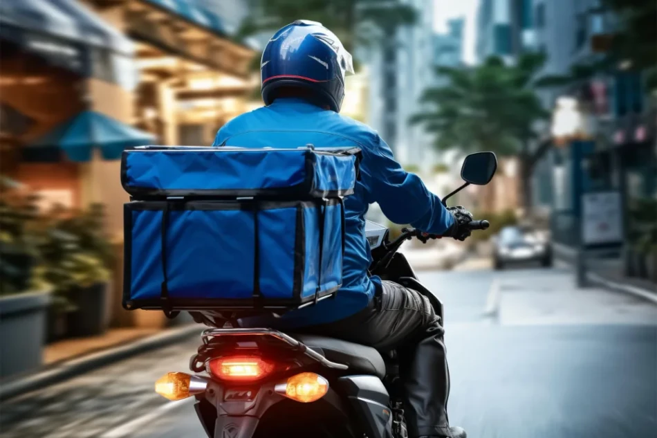 Motoboy com mochila de entrega azul e capacete trafegando pela cidade com sistema de rastreamento para moto ativo